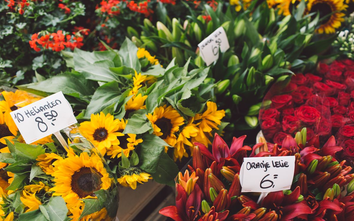 Farmer's market stall with seasonal flowers and a handwritten price board