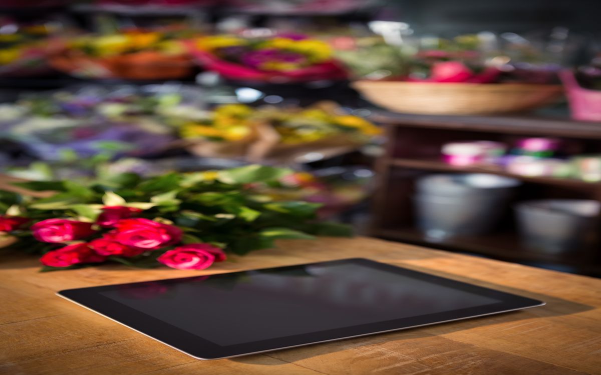 Market stall at the end of a day with remaining flower bouquets and a closed tablet on the counter