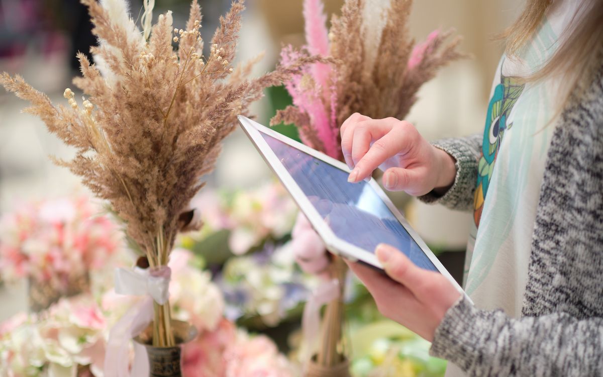 Market stall with flower arrangements and a small tablet showing a payment interface